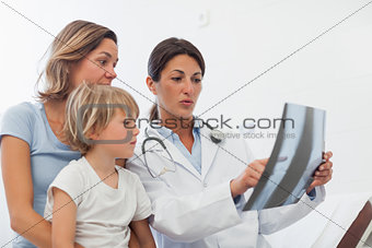 Doctor examining the X-ray next to a mother and her child
