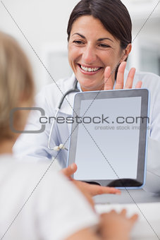 Smiling doctor showing a tablet computer to a child