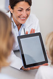 Smiling doctor presenting a tablet computer