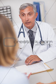 Doctor sitting at his desk looking at a patient