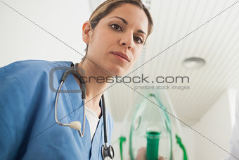 Nurse holding an oxygen mask while looking at camera