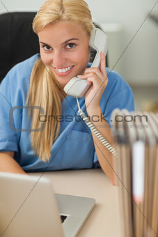 Blonde nurse calling while looking at camera