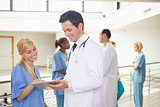 Smiling doctor showing a clipboard to nurse