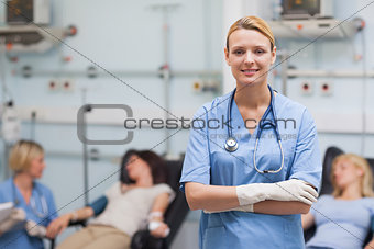 Nurse standing with arms crossed next to patients