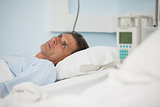 Thoughtful patient lying on a medical bed