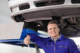 Mechanic holding a spanner below a car