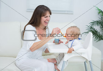 Mother sitting in a sofa while feeding a baby