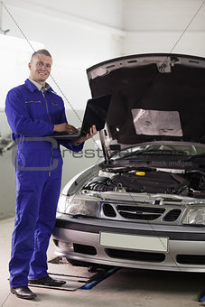 Mechanic standing while holding a computer