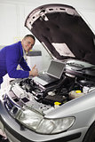 Mechanic repairing a car with a computer