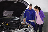 Mechanic showing a par of the engine to a woman