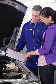 Woman looking at the clipboard next to a car