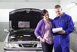 Mechanic showing a paper in a clipboard to a woman