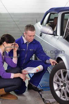 Mechanic touching the car wheel while looking at it
