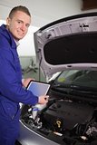 Smiling mechanic testing an engine with a tablet computer
