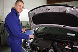 Mechanic looking at camera while holding a tablet computer