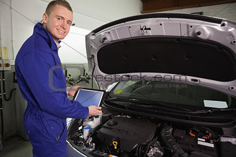Mechanic looking at camera while holding a tablet computer