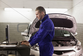Mechanic standing while looking at a computer