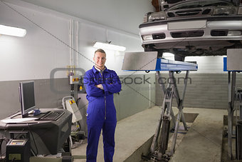 Smiling mechanic standing next to a car