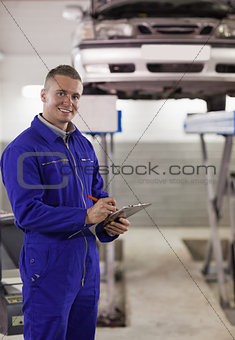 Smiling mechanic writing on a clipboard