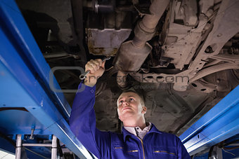 Concentrated mechanic repairing below of a car