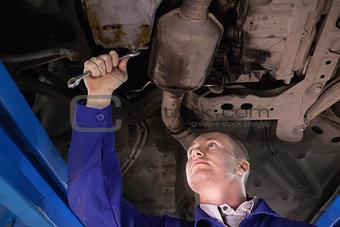 Concentrated mechanic looking at the below of a car