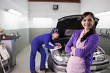 Woman smiling with arms crossed next to a mechanic