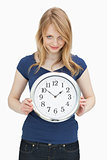 Woman looking at camera while holding a clock