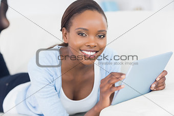 Black woman smiling while holding a tablet computer