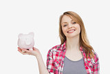 Woman holding a piggy bank while looking at camera