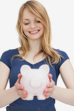 Blonde woman holding a piggy bank while looking it