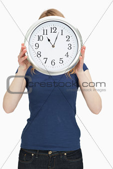 Woman holding a clock in front of her face