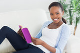 Black woman sitting on a sofa while holding a book