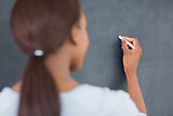 Focus on a black woman writing on a blackboard