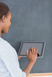 Woman using a tablet computer next to a blackboard