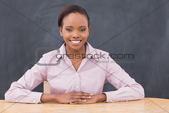 Teacher smiling while putting her hands on desk