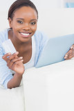 Black woman holding a credit card and a tablet computer
