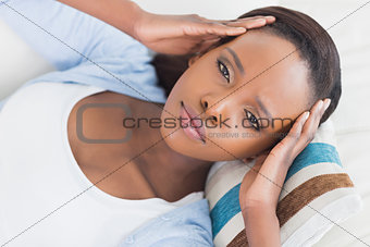 Black woman lying while putting hands on temples