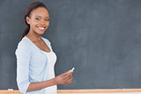 Black woman holding a chalk next to a blackboard