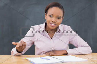 Teacher sitting at desk next to a notebook