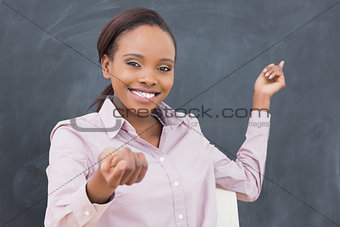 Black teacher smiling while showing the blackboard