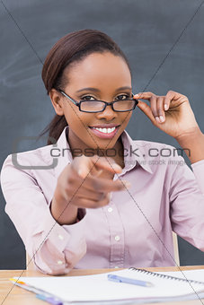 Teacher touching her glasses while sitting at desk