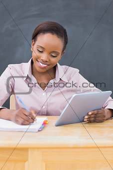 Teacher holding an ebook while writing
