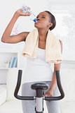 Black woman on an exercise bike drinking