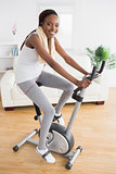 Black woman doing exercise bike with headphones