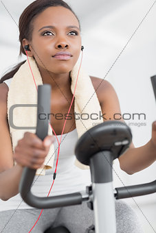 Concentrated woman doing exercise bike while listening music
