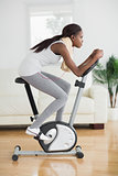 Side view of a concentrated black woman doing exercise bike