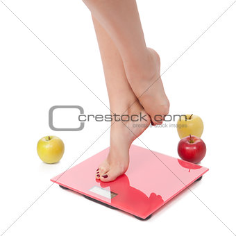 Woman perfect shaped legs on scale with apple