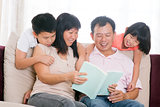 Parents and children reading books at home.