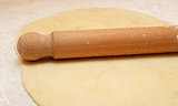 Fresh pastry rolled out with a wooden rolling pin