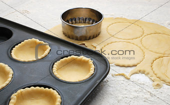 Pastry circles cut and lining a metal bun tin